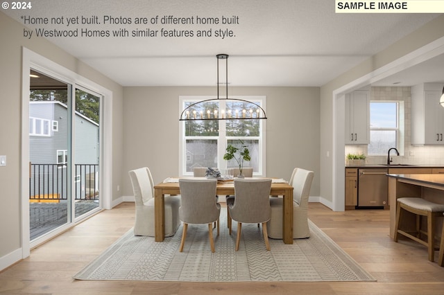 dining space featuring light wood-type flooring, a wealth of natural light, and an inviting chandelier