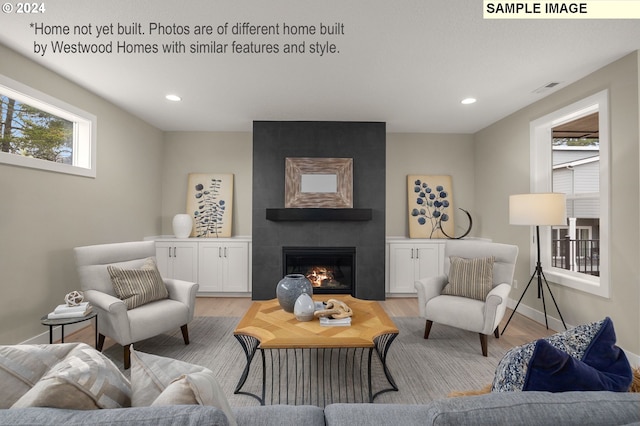 living room featuring a tile fireplace, light wood-type flooring, and plenty of natural light