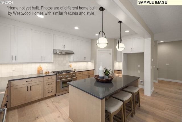 kitchen with white cabinetry, hanging light fixtures, a kitchen island, light hardwood / wood-style flooring, and stainless steel stove