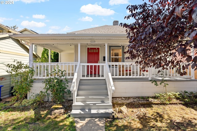 view of front of home featuring covered porch and a chimney