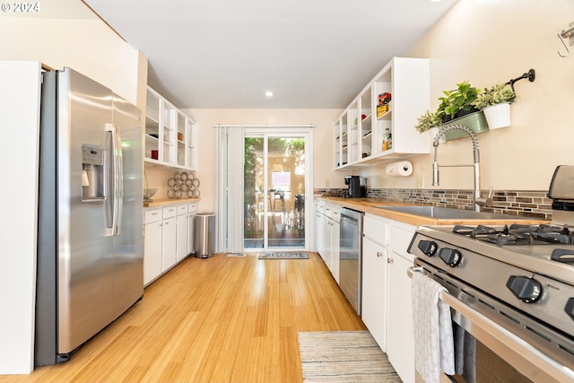 kitchen featuring open shelves, white cabinets, and stainless steel appliances