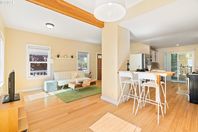 interior space with beamed ceiling, light wood-type flooring, a wealth of natural light, and baseboards