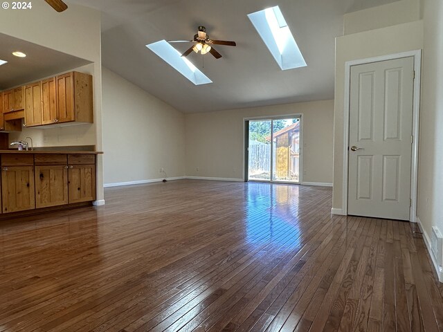 unfurnished living room with a skylight, ceiling fan, hardwood / wood-style flooring, sink, and high vaulted ceiling