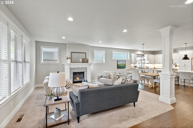 living room featuring decorative columns, light hardwood / wood-style floors, and a fireplace