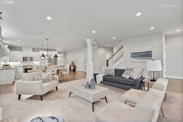 living room with a notable chandelier, light hardwood / wood-style floors, and ornate columns