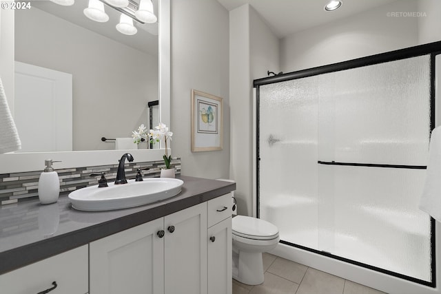 bathroom featuring vanity, backsplash, toilet, and a shower with shower door