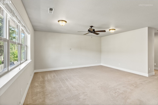 empty room with a textured ceiling, light carpet, and ceiling fan