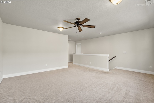 unfurnished room with ceiling fan, light colored carpet, and a textured ceiling