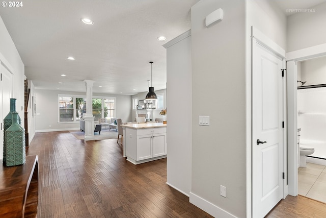 corridor with decorative columns and hardwood / wood-style flooring