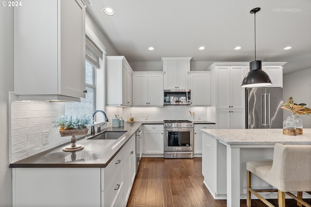 kitchen featuring appliances with stainless steel finishes, hanging light fixtures, sink, and white cabinets