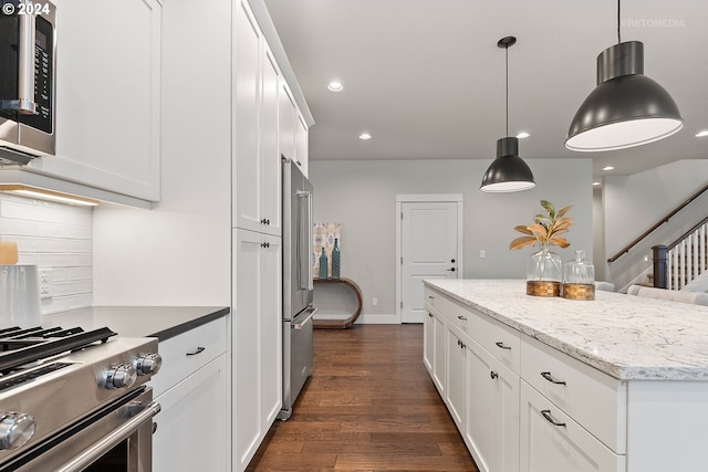 kitchen featuring appliances with stainless steel finishes, hanging light fixtures, dark wood-type flooring, light stone counters, and white cabinets