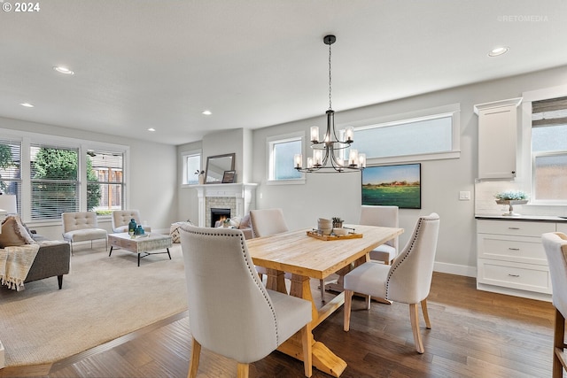 dining space featuring an inviting chandelier, light wood-type flooring, and a fireplace