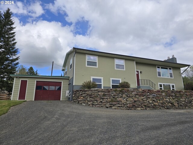 raised ranch featuring a garage and an outbuilding