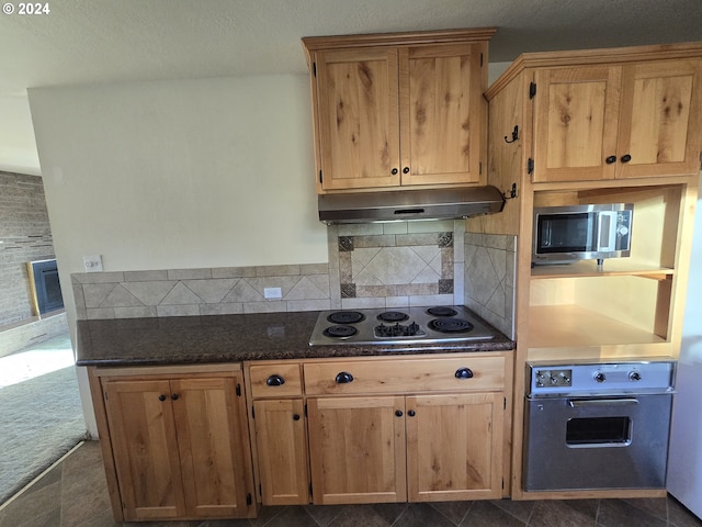 kitchen featuring wall oven, backsplash, dark colored carpet, dark stone countertops, and electric stovetop