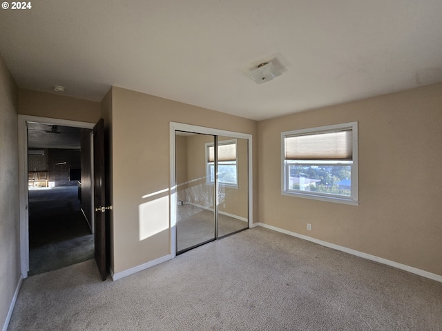 unfurnished bedroom with a closet, light colored carpet, and multiple windows