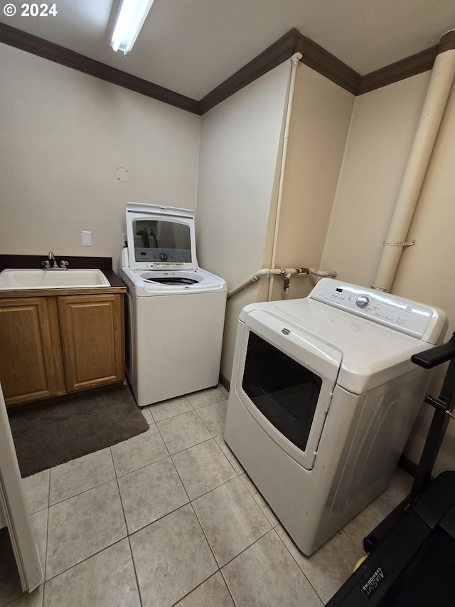 washroom featuring sink, cabinets, washer and dryer, light tile patterned floors, and crown molding