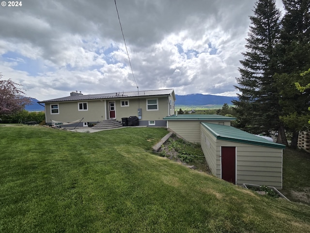 back of property with a mountain view, a shed, and a yard