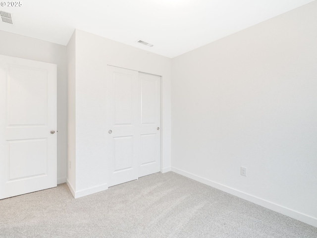 unfurnished bedroom featuring a closet and light carpet