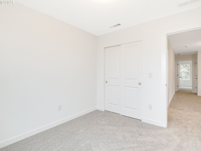 unfurnished bedroom with light carpet and a closet