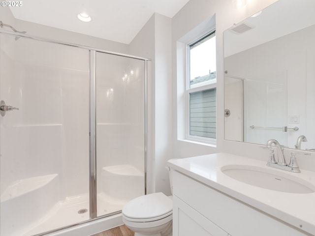 bathroom featuring a shower with door, vanity, and toilet