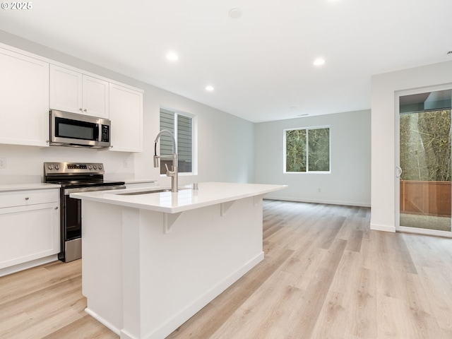 kitchen featuring white cabinetry, sink, a center island with sink, and appliances with stainless steel finishes