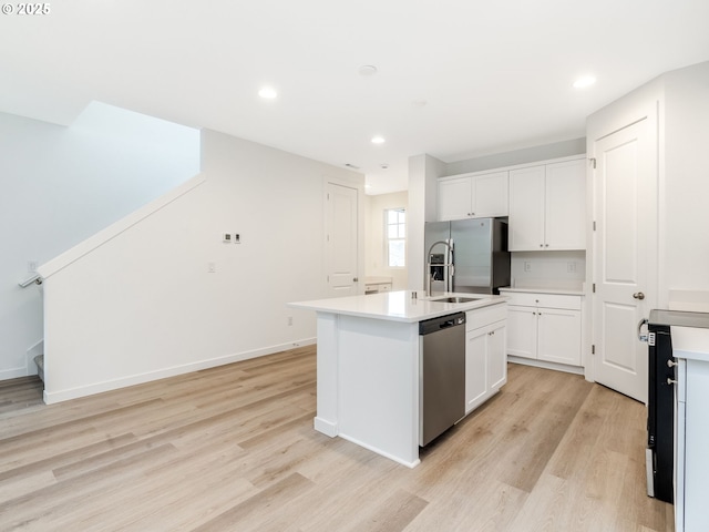 kitchen with appliances with stainless steel finishes, light hardwood / wood-style floors, a center island with sink, and white cabinets