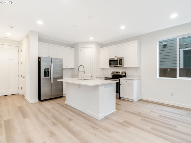 kitchen with sink, a center island with sink, light wood-type flooring, stainless steel appliances, and white cabinets