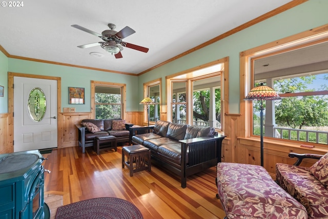 living room with crown molding, light hardwood / wood-style flooring, ceiling fan, and a wood stove