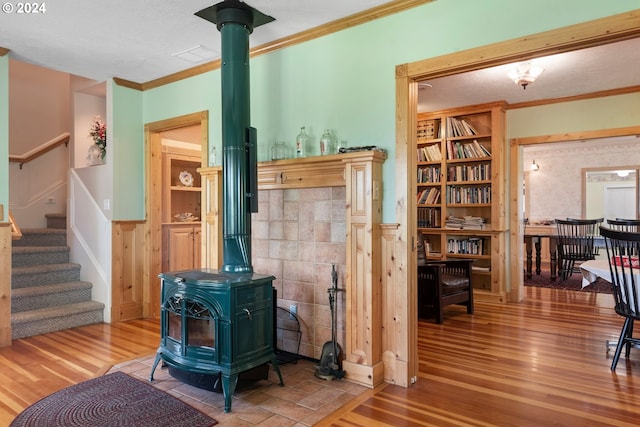 living room featuring hardwood / wood-style flooring, ornamental molding, and a wood stove