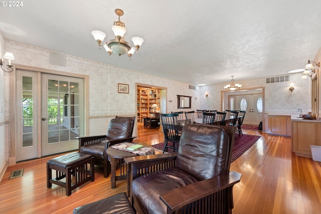 living room with french doors, an inviting chandelier, and light hardwood / wood-style flooring