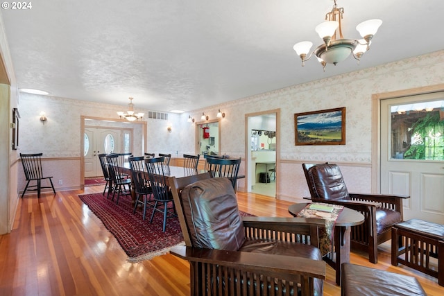 dining room featuring hardwood / wood-style flooring, a textured ceiling, and a notable chandelier