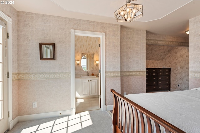 bedroom with ensuite bathroom, sink, and a notable chandelier