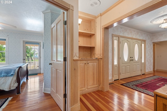 entryway with ornamental molding and light wood-type flooring