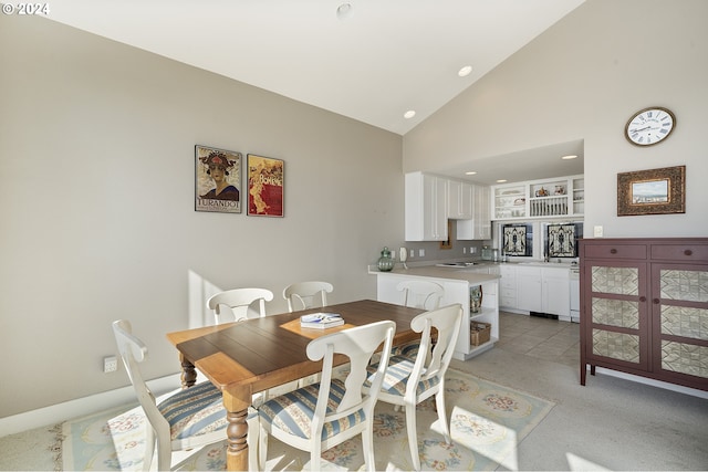 carpeted dining area featuring high vaulted ceiling and built in shelves