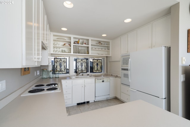 kitchen with white appliances, sink, light tile patterned floors, and white cabinets