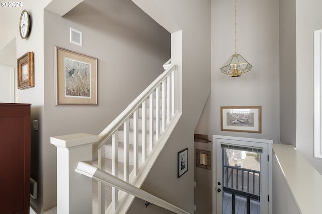 staircase with a high ceiling and an inviting chandelier