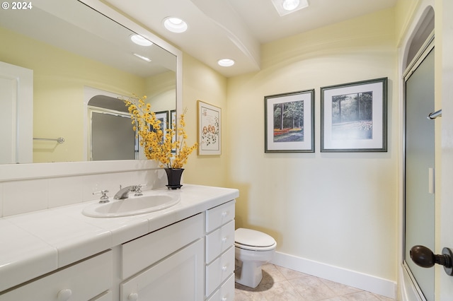 bathroom featuring tile patterned floors, toilet, vanity, and a shower with shower door