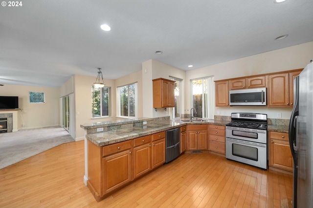 10909 SW Adele Dr, Portland, OR 97225 - kitchen with stainless steel appliances, open floor plan, light wood-style floors, a sink, and tile counters