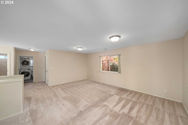 10909 SW Adele Dr, Portland, OR 97225 - unfurnished living room featuring stacked washing machine and dryer, light carpet, and plenty of natural light