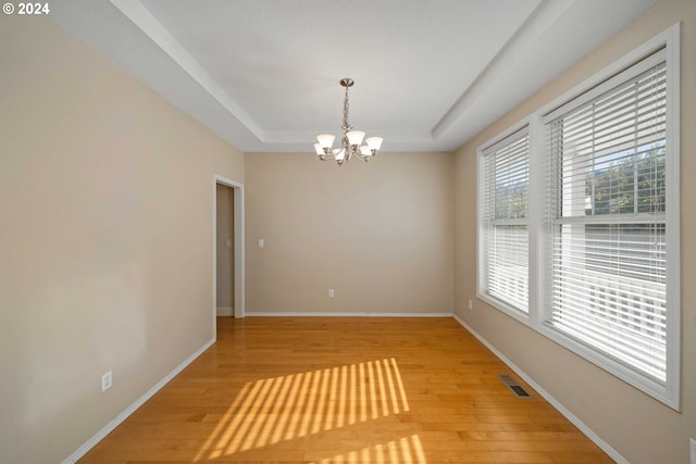 10909 SW Adele Dr, Portland, OR 97225 - spare room with a tray ceiling, a chandelier, light wood-style flooring, and baseboards