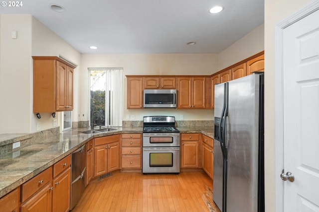 10909 SW Adele Dr, Portland, OR 97225 - kitchen with appliances with stainless steel finishes, a sink, brown cabinetry, light wood-style floors, and recessed lighting