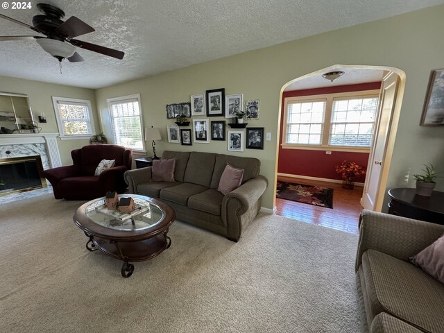 living room featuring ceiling fan, a textured ceiling, a premium fireplace, and carpet