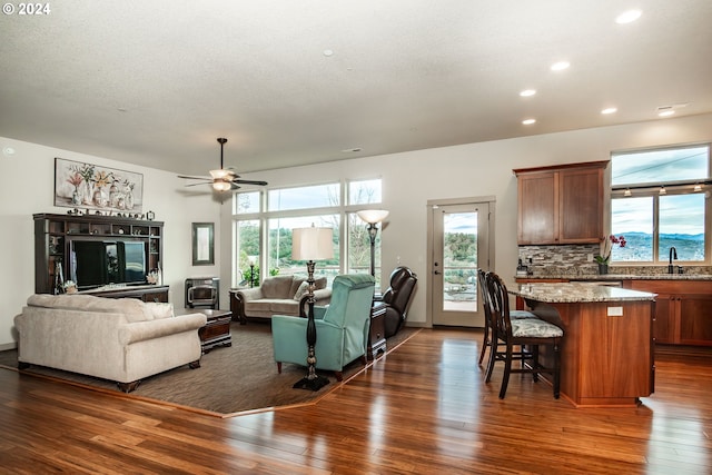 living room featuring a textured ceiling, ceiling fan, dark wood-type flooring, and sink