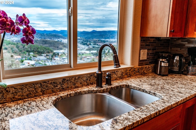 interior details featuring a mountain view, light stone countertops, sink, and tasteful backsplash