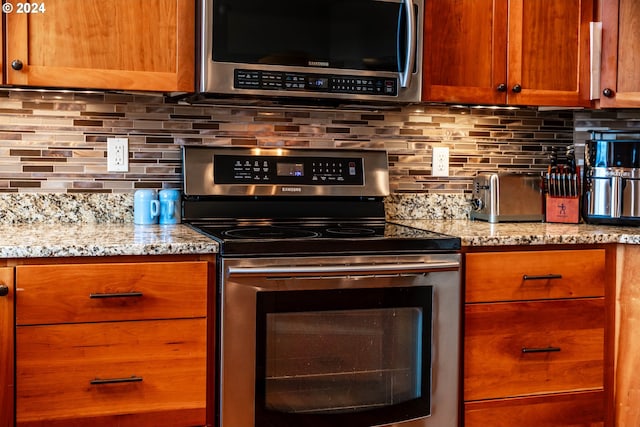 kitchen featuring decorative backsplash, stainless steel appliances, and light stone counters