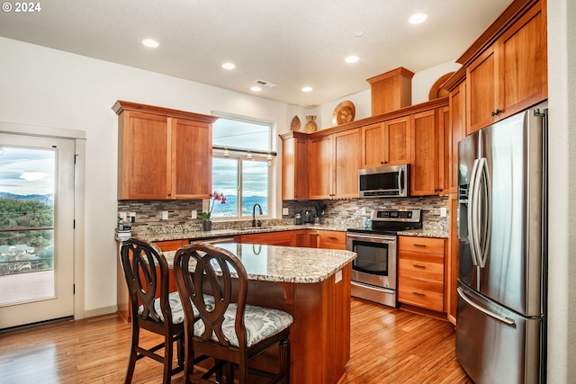 kitchen featuring light stone countertops, tasteful backsplash, a breakfast bar, a kitchen island, and appliances with stainless steel finishes