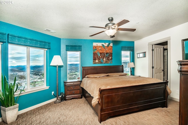 bedroom with a textured ceiling, light colored carpet, and ceiling fan