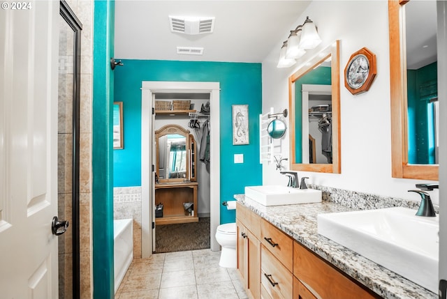 bathroom featuring tile patterned floors, a washtub, toilet, and vanity