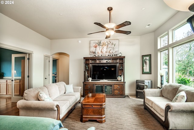 living room featuring a wood stove and ceiling fan