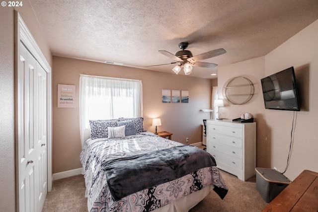 bedroom featuring a closet, a textured ceiling, light colored carpet, and ceiling fan